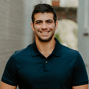 Dominic George smiling headshot with a navy blue polo