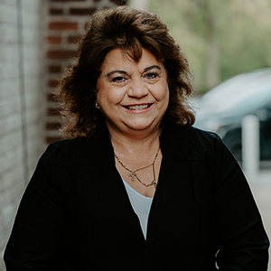 Nancy Amata headshot smiling with white shirt and black blouse