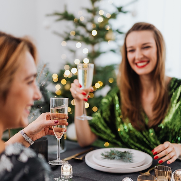 Two woman drinking champagne at a classy holiday party